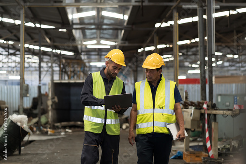 Two male engineer worker discuss and working together in industry factory. Male engineer repairing or maintenance CNC machine in factory