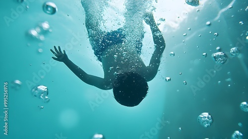 Vibrant image of an energetic child diving headfirst into a sparkling pool creating a dramatic splash above the surface and leaving a trail of bubbles underwater photo