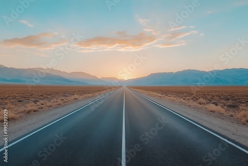 Long straight country road with great mountains in horizon and clear blue sky above