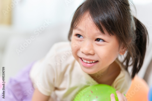 Asian kid girl with multicolor balloons, Cheerful girl playing air balls photo