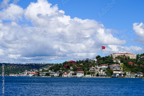 Panoramic view of Istanbul\'s Bosphorus featuring hillside villas and the Turkish flag against a vibrant sky photo