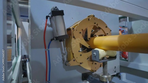 Focused view on industrial machinery producing yellow PVC pipes in a modern factory environment, highlighting advanced manufacturing techniques and industrial equipment.