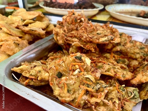 Pile of bakwan sayur fried cooked indonesian dish isolated on horizontal ratio warteg table environment background.  photo