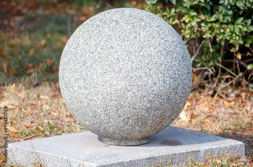 A large grey stone ball sits on a concrete base A large grey stone ball sits on a concrete base