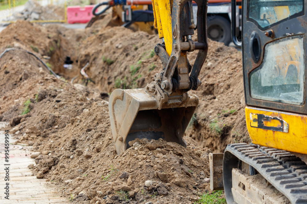 Fototapeta premium A yellow and black construction vehicle is digging a trench