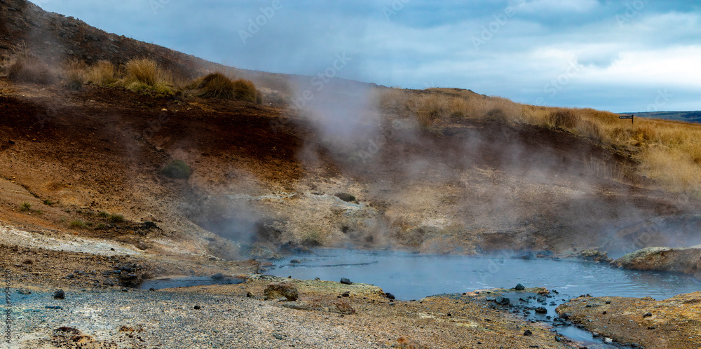 A steamy, rocky landscape with a small body of thermal waters A steamy, rocky landscape with a small body of thermal waters