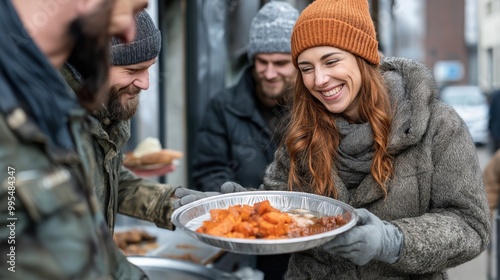 A group of individuals gathers on a busy street to distribute warm meals, showcasing community spirit as they share food and smiles on a cold day