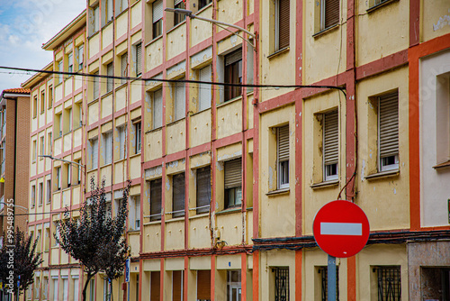 The image features a multi-story residential building with a classic, rustic look, combining brick and white concrete walls. It reflects a typical urban or suburban setting, with evenly spaced windows photo
