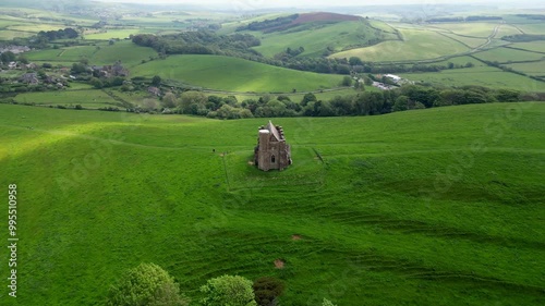 Aerial drone orbit shot of St Catherine's Chapel, Abbotsbury, Dorset, on England's South Coast with views of Chesil Beach and surrounding lush green fields. A shard of sunlight coincidentally passes. photo