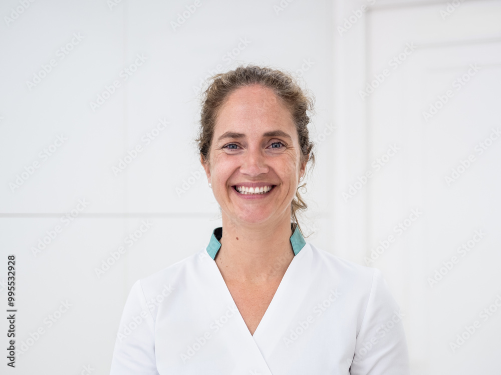 © BeatrizHerrera - A female medical worker wearing scrubs in a bright clinic, ready to greet patients with a warm smile, looking at camera and showcasing a welcoming atmosphere. © BeatrizHerrera - A female medical worker wearing scrubs in a bright clinic, ready to greet patients with a warm smile, looking at camera and showcasing a welcoming atmosphere.