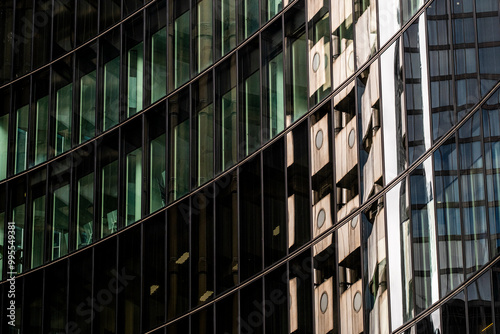 Abstract reflection patterns created on the curved glass facade of a modern high-rise building, capturing intricate details and play of light and shadows.