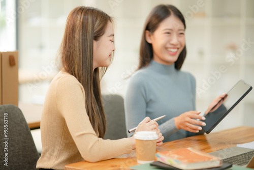 Asian businesswoman using a tapered laptop, sitting and talking in the office