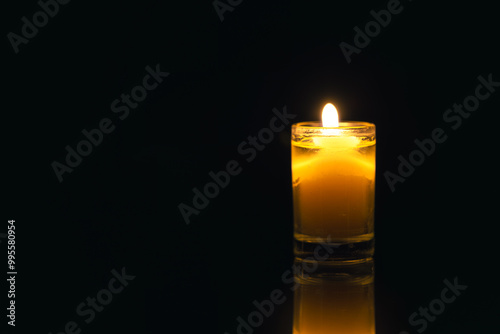 Burning candle on black background with backlight. Memorial Day.