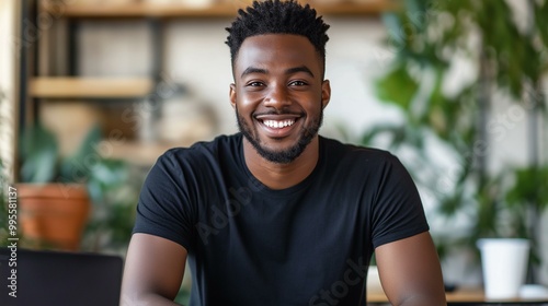 Young Professional Smiling in Black T-Shirt in Casual Office Setting with Green Plants