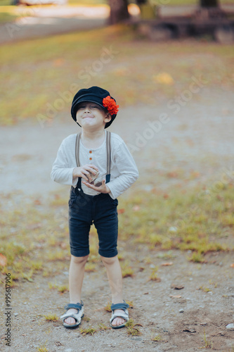 Funny little boy in retro hat with red flower holding pebbles photo