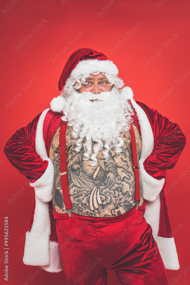 Funny crazy santa claus with tattoo having fun on a red colored background Funny crazy santa claus with tattoo having fun on a red colored background