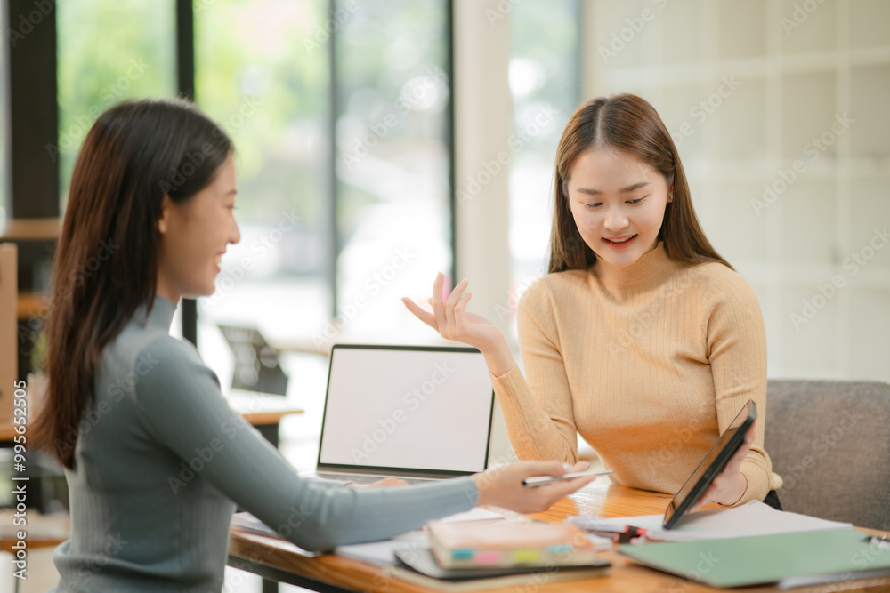 Asian businesswoman using a tapered laptop, sitting and talking in the office Asian businesswoman using a tapered laptop, sitting and talking in the office