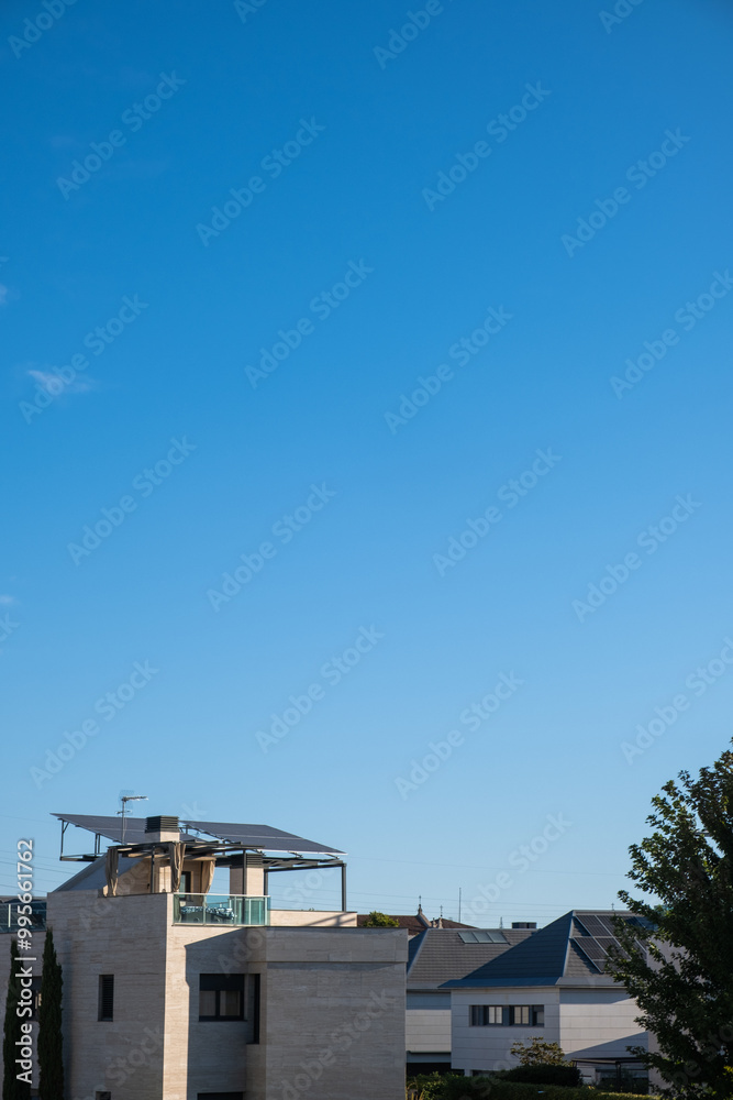 Sunny day in an urbanization of individual chalets with modern architecture. They have photovoltaic solar panels on the roofs, the sky is clear and blue. ecological and sustainable urbanism Sunny day in an urbanization of individual chalets with modern architecture. They have photovoltaic solar panels on the roofs, the sky is clear and blue. ecological and sustainable urbanism