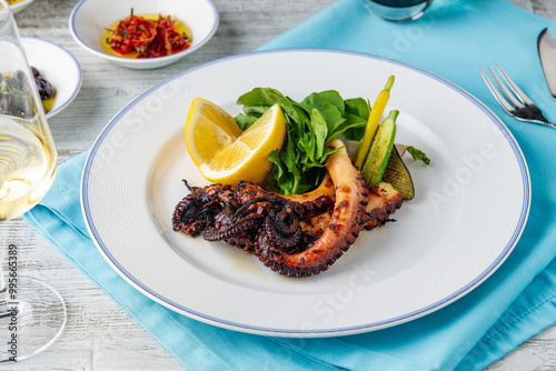 Grilled octopus with arugula and mini vegetables on a white porcelain plate