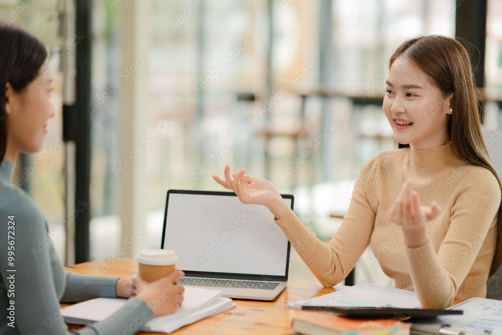 Fototapeta premium Asian businesswoman using a tapered laptop, sitting and talking in the office