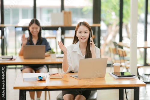 Two women work with tablets, work and chatting about paperwork and graphs.