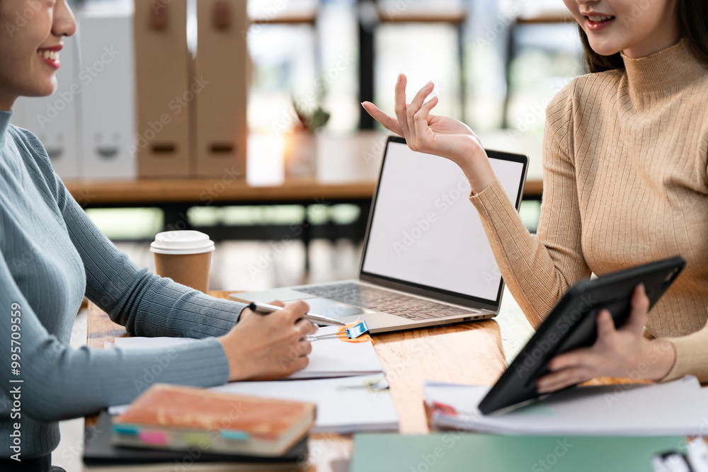 Two asian business women sitting at desk using tablet and talking about analyzing documents in workplace office Two asian business women sitting at desk using tablet and talking about analyzing documents in workplace office