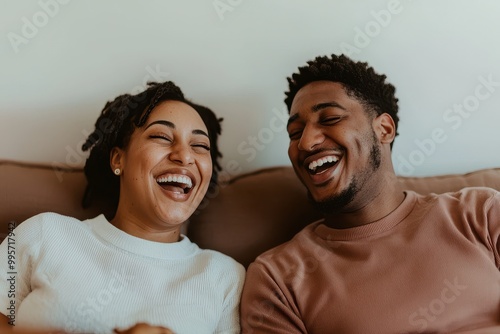 A joyful couple shares a moment of laughter while seated together, showcasing their connection and happiness.