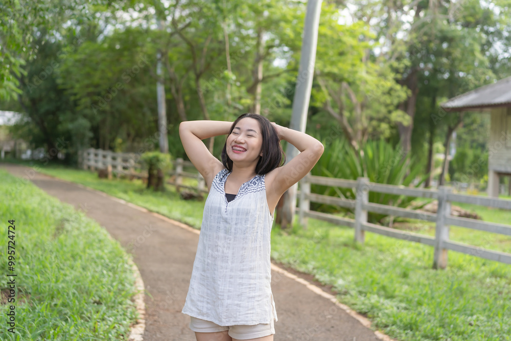 Asian young woman with her hands crossed behind her head, smiling beautifully, enjoying a happy moment, carefree, eyes closed, relaxing, healthy lifestyle. Asian young woman with her hands crossed behind her head, smiling beautifully, enjoying a happy moment, carefree, eyes closed, relaxing, healthy lifestyle.