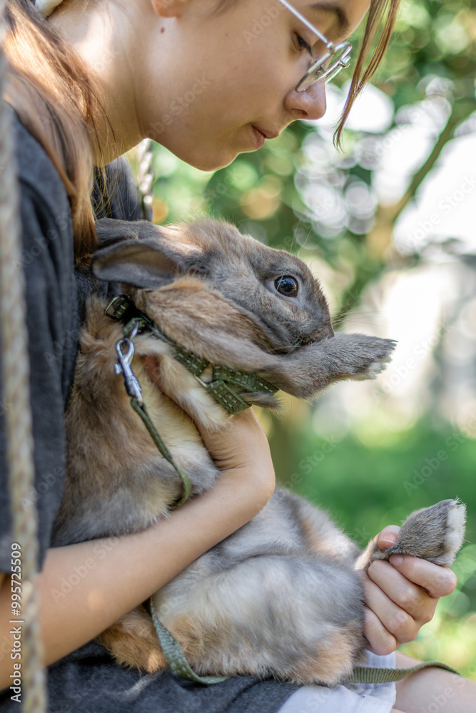 A girl plays with a domestic rabbit on the street. Pet concept. A girl plays with a domestic rabbit on the street. Pet concept.