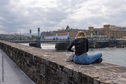 Tourist sitting at the mouth of the Urumea River in San Sebastián. Gipuzkoa, Basque Country. photo