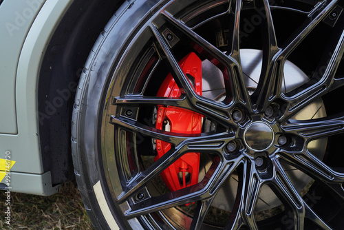 Alloy wheel with calipers and racing brakes of the sport car. Racing brake disc and low profile tyres. Race car test driving. Lower-profile tires of drag and drift cars. High-performance sports cars.