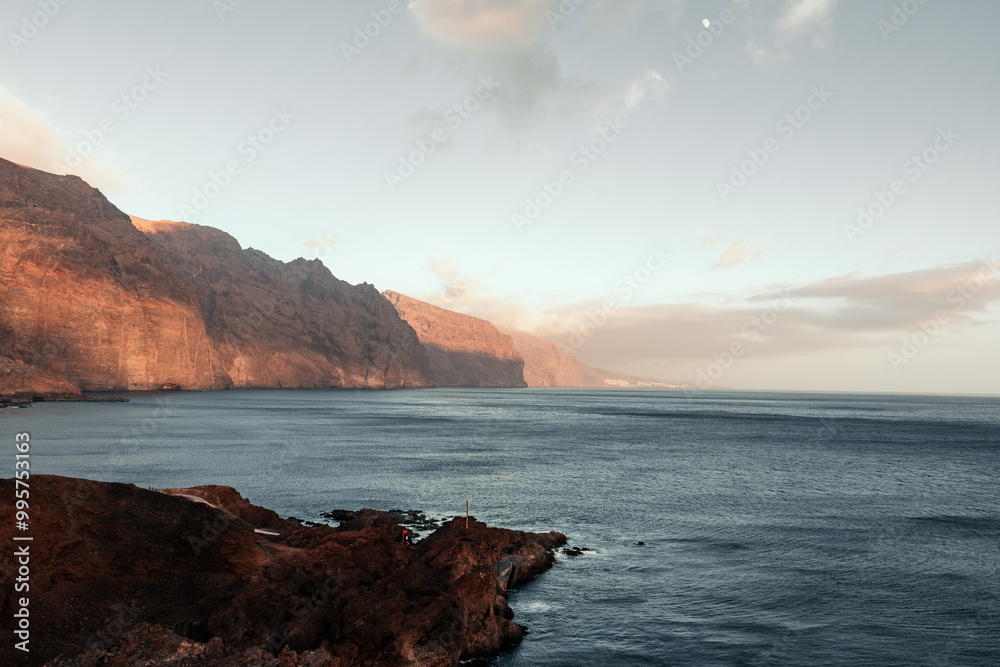 Breathtaking sunset view of rugged cliffs Los Gigantes meeting calm ocean waters Breathtaking sunset view of rugged cliffs Los Gigantes meeting calm ocean waters