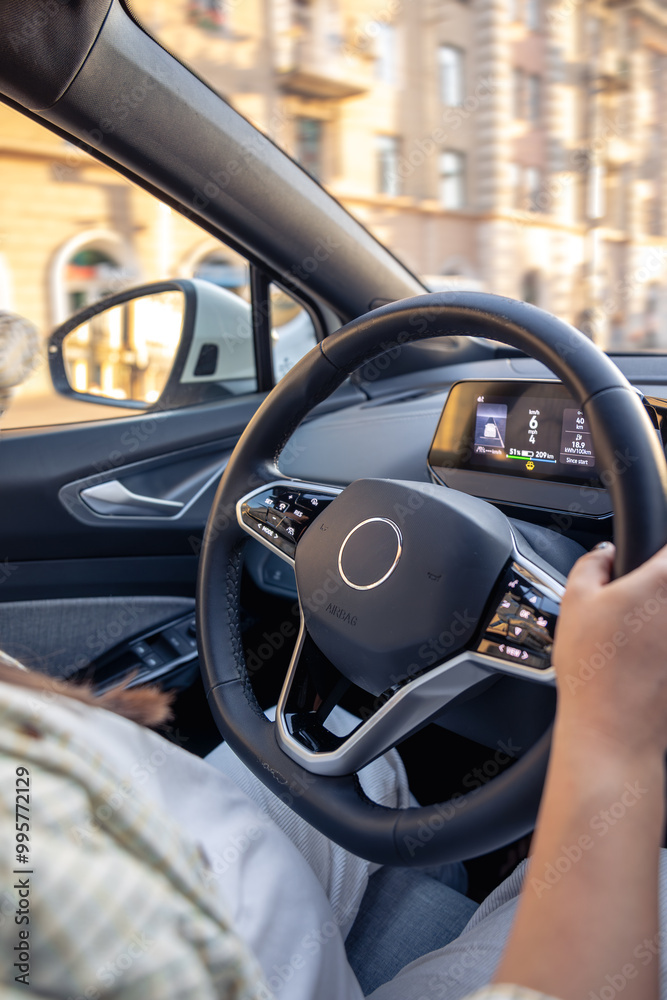 Young woman driving a car. Hands on the wheel. View from the back to the road. Young woman driving a car. Hands on the wheel. View from the back to the road.