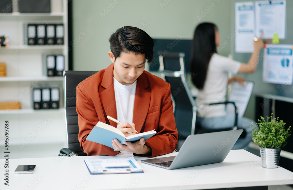 Confident Asian man with a smile standing holding notepad and tablet at office. Confident Asian man with a smile standing holding notepad and tablet at office.