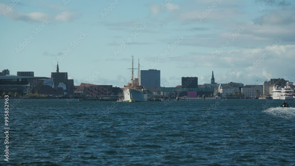 Scenic view of Copenhagen harbor with towering city skyline and royal yacht of the Danish Crown called Dannebrog. Perfect for travel documentaries. Scenic view of Copenhagen harbor with towering city skyline and royal yacht of the Danish Crown called Dannebrog. Perfect for travel documentaries.