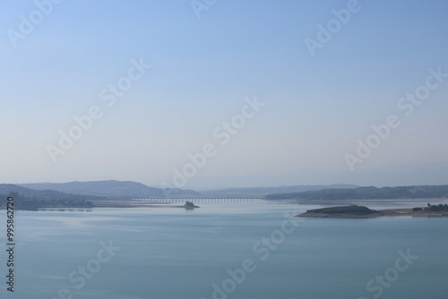 lake with a bridge and a cloudy sky