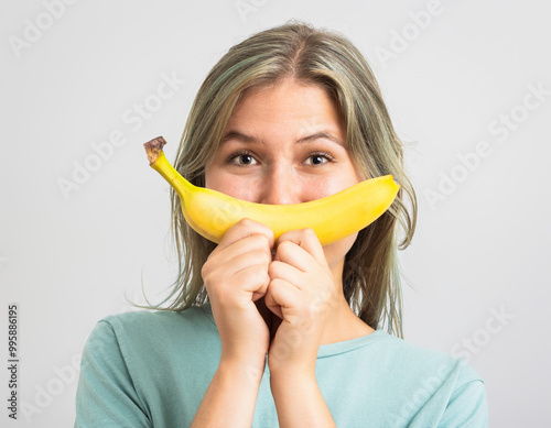 Funny young womand holding a banana in front of her face. photo