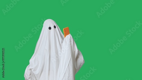 Canvastavla Funny halloween ghost in white sheet talking on smartphone by video call, isolated on chroma key green screen background