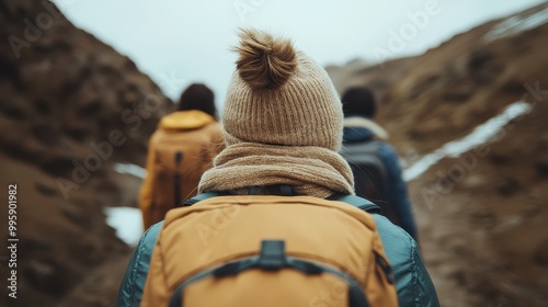 Three hikers dressed in warm, colorful clothing trek through a rugged, rocky terrain with backpacks, exploring the outdoors on a cold day, emphasizing adventure and exploration. photo