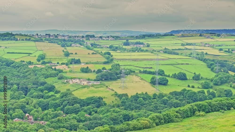A tranquil countryside landscape with a patchwork of green fields bordered by trees under an overcast sky. Power lines intersect the scene, adding a contrast to the natural setting A tranquil countryside landscape with a patchwork of green fields bordered by trees under an overcast sky. Power lines intersect the scene, adding a contrast to the natural setting
