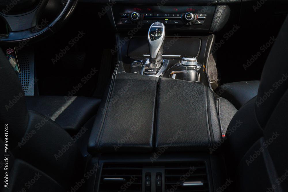 View from the back seat of the car on the middle console with the automatic gearshift handle, radio. Dark leather interior. View from the back seat of the car on the middle console with the automatic gearshift handle, radio. Dark leather interior.