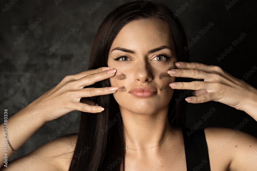 Obraz premium A woman applies camouflage make-up to her face