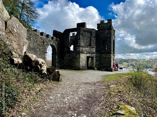 Dramatic ruins of a stone castle tower with archway overlooking a scenic landscape under a bright sky. The Victorian building is the Claife Viewing Station which hosted the wealthy in days gone by photo