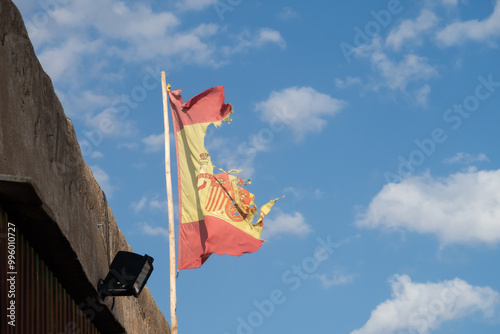 Una bandera de España rasgada ondea contra el cielo azul
