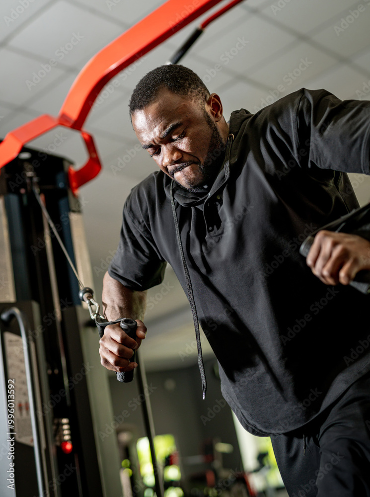 Man exercising on a cable machine in a gym. Man exercising on a cable machine in a gym.
