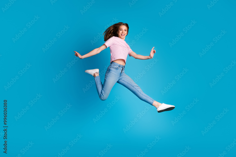 Full length photo of lovely young lady running hurry dressed stylish striped pink garment isolated on blue color background Full length photo of lovely young lady running hurry dressed stylish striped pink garment isolated on blue color background