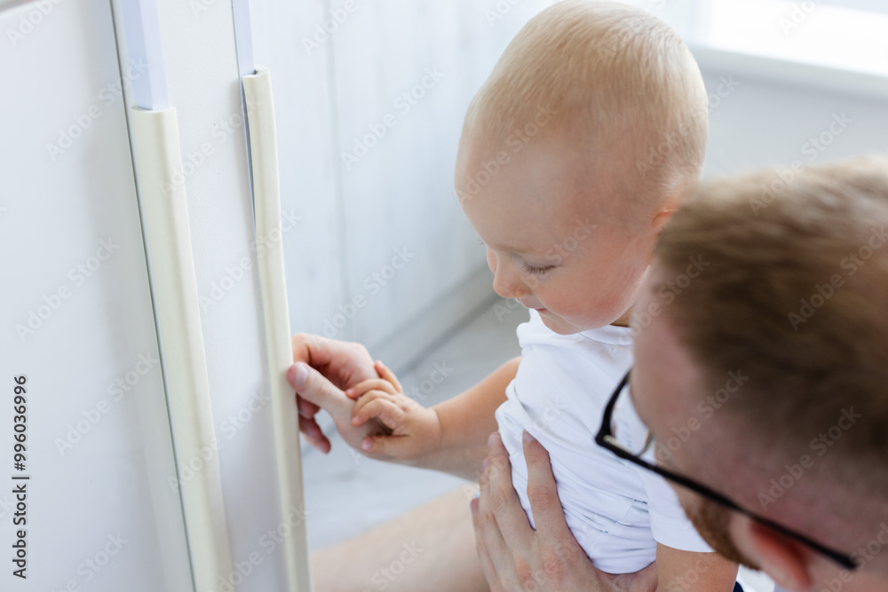 Father explain to his child that he must be careful with dangerous corners of walls and furnitures at home. Father explain to his child that he must be careful with dangerous corners of walls and furnitures at home.