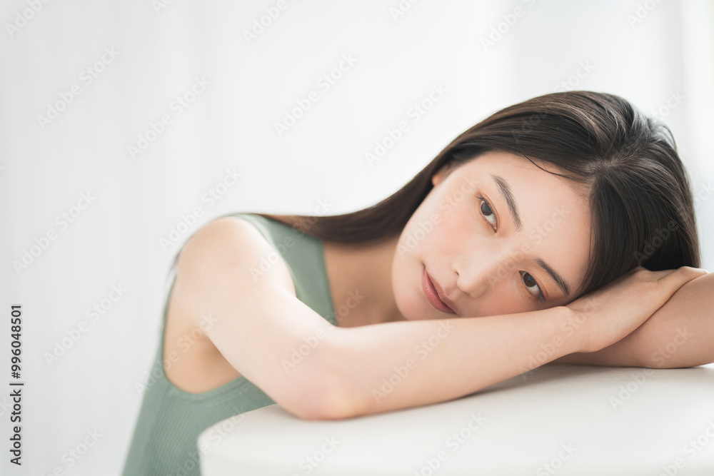 Portrait of a young beautiful Asian woman. She has straight black hair. She is leaning on the table. Portrait of a young beautiful Asian woman. She has straight black hair. She is leaning on the table.