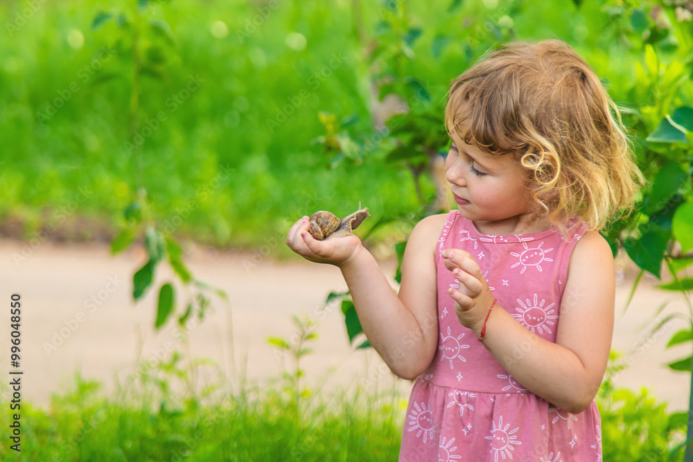 Child holding a snail on his hand. Selective focus. Child holding a snail on his hand. Selective focus.