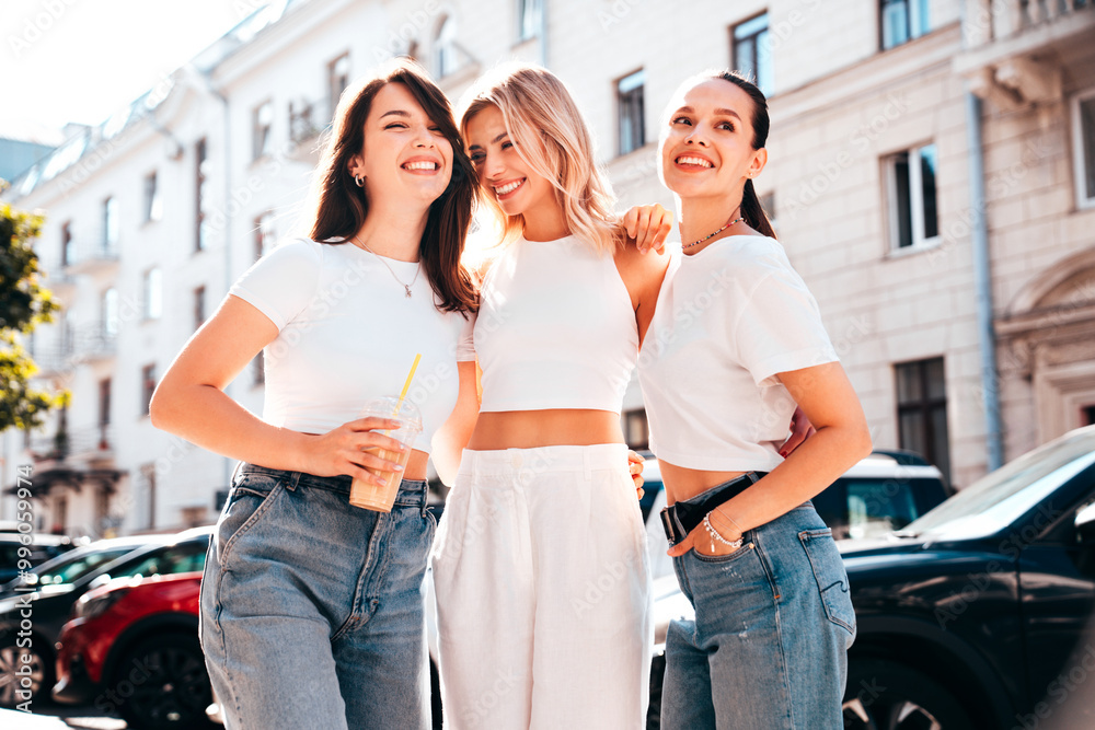 Obraz premium Three young beautiful smiling hipster female in trendy summer white t-shirt and jeans clothes. Sexy carefree women posing in the street. Positive models having fun, talking, chatting. Going crazy